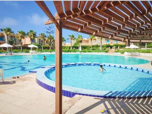 a swimming pool at a resort with people in it at قرية nice 1 الساحل الشمالي in Dawwār ‘Abd Allāh