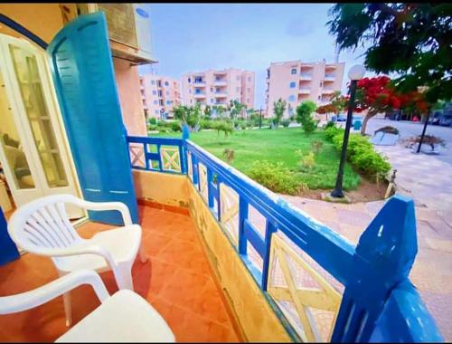 a blue railing with two white chairs on a balcony at قرية nice 1 الساحل الشمالي in Dawwār ‘Abd Allāh