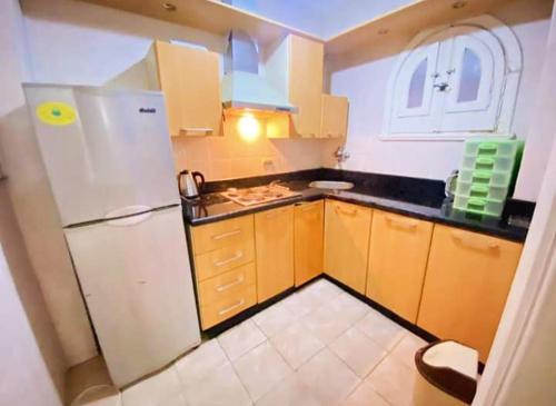 a kitchen with a white refrigerator and wooden cabinets at قرية nice 1 الساحل الشمالي in Dawwār ‘Abd Allāh