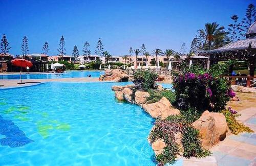a large swimming pool with rocks in a resort at قرية nice 1 الساحل الشمالي in Dawwār ‘Abd Allāh