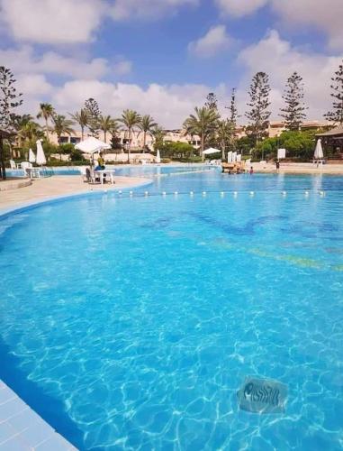 a large pool of blue water in a resort at قرية nice 1 الساحل الشمالي in Dawwār ‘Abd Allāh