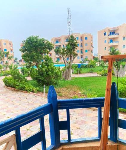 a blue fence in front of a park with palm trees at قرية nice 1 الساحل الشمالي in Dawwār ‘Abd Allāh