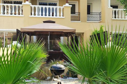 a building with an umbrella and plants in front of it at Spacious Villa with terrace close to the sea in Ras al Khaimah
