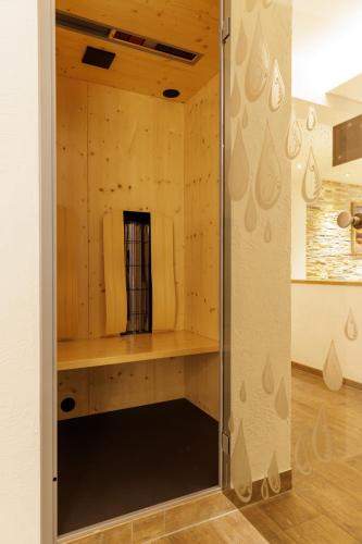 a shower in a room with a wooden wall at Apartmenthaus Goldeck in Ried im Oberinntal