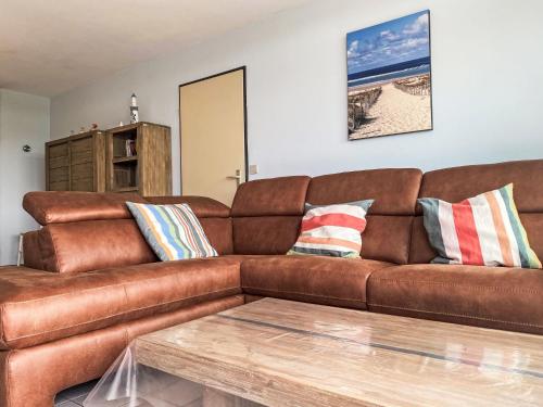 Un sofá de cuero marrón en una sala de estar con una mesa. en Apartment Ref 602 by Interhome, en Bredene