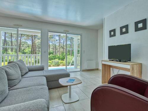 a living room with a couch and a tv at Holiday Home Eden Parc by Interhome in Lacanau-Océan