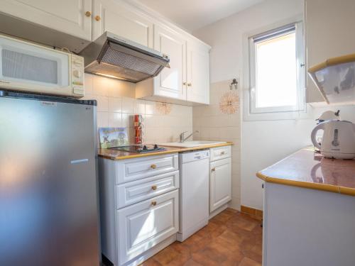 une cuisine avec des armoires blanches et un réfrigérateur en acier inoxydable dans l'établissement Studio Le Weekend by Interhome, à La Madrague