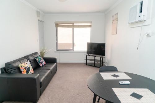 a living room with a black couch and a table at Apartment 25 Burswood in Perth
