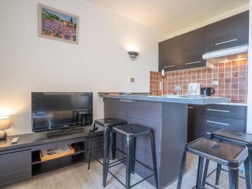 Il comprend une cuisine avec un bar avec des tabourets et une télévision. dans l'établissement Apartment Les Aigues Marines-58 by Interhome, à Saint-Cyr-sur-Mer