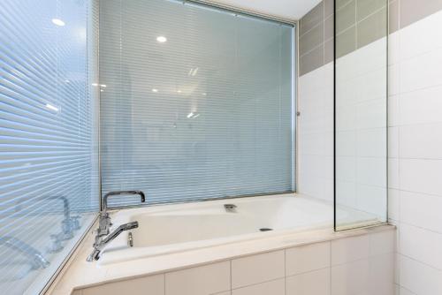 a bathroom with a tub and a glass window at LeafIN Hotel Beijing Minzuyuan l Bird's Nest in Beijing