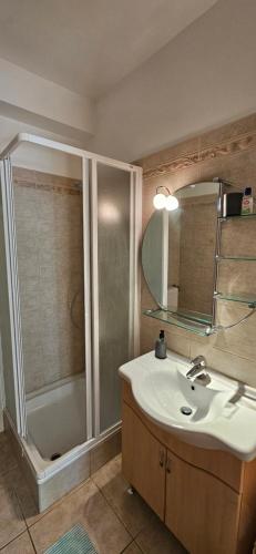 オルフェにあるChill & More Apartmanの洗面台、シャワー、鏡を備えたバスルーム