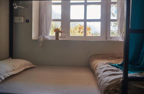 een slaapkamer met 2 bedden en een raam bij Hostelgia in Manāli