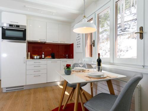 a kitchen with white cabinets and a table with a bottle of wine at Apartment Residenza Chesa Margun 710-5 by Interhome in Surlej