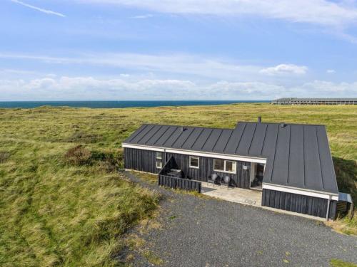 a black house in the middle of a field at Holiday Home Simona - 300m from the sea by Interhome in Hirtshals