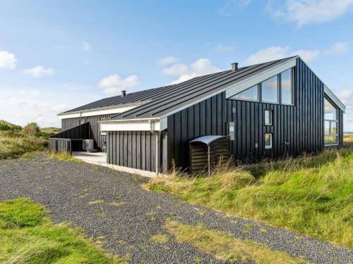 a black house on the side of a hill at Holiday Home Simona - 300m from the sea by Interhome in Hirtshals