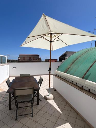 a table and chair with an umbrella on a roof at Casa nel Liberty in Canicattini Bagni