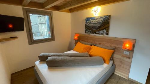 a bedroom with a bed with orange pillows and a window at beb Aria di Montagna in Forcola