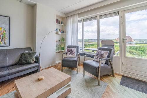 a living room with a couch and chairs and windows at Appartementencomplex Juliana 146 in De Koog
