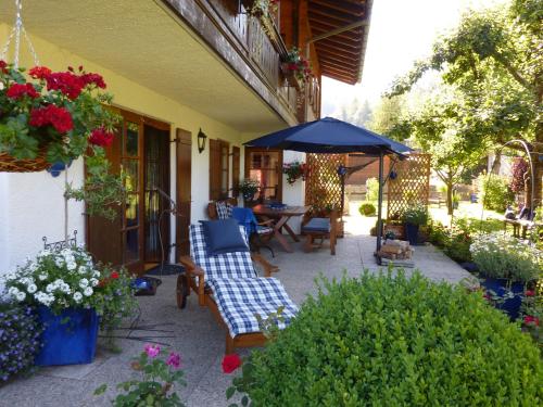 a patio with a table and chairs and an umbrella at Gästehaus Schönfeld in Reit im Winkl