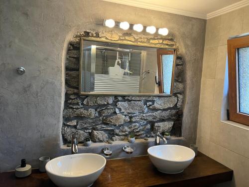 a bathroom with two sinks and a stone wall at Cozy Hide Away Frantato in Akamatra
