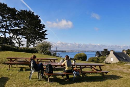 two women sitting on benches at a picnic table at Ostal Île de Batz - Auberge de jeunesse in Île de Batz