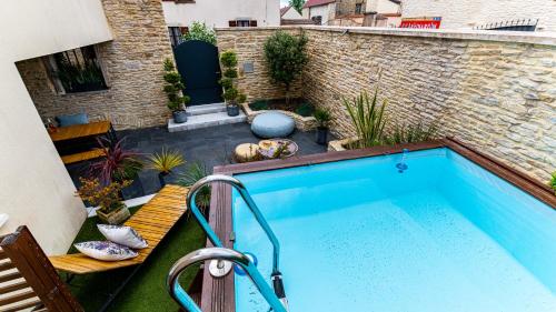 - une piscine avec banc à côté d'un bâtiment dans l'établissement La Maison d'Ernest - Climatisée - Circuit DIJON PRENOIS, à Prenois