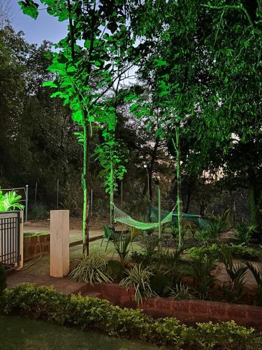 a green hammock in a park with trees at Jessica’s Vacation Home in Banda
