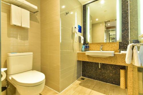 a bathroom with a toilet and a sink and a mirror at Holiday Inn Express Shanghai Jiading Industry Park by IHG in Jiading