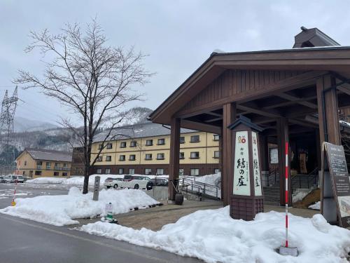 a building with snow on the ground in front of it at Onyado Yuinosho, Shirakawago in Shirakawa