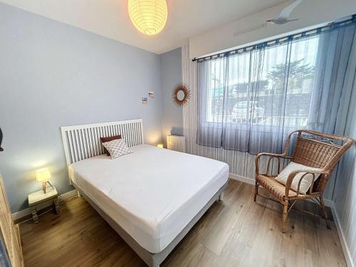 une chambre avec un lit, une chaise et une fenêtre dans l'établissement Bel appartement rénové au cœur de Jullouville, 100m de la plage, 1 chambre, 4 couchages, parking privé - FR-1-361-72, à Jullouville