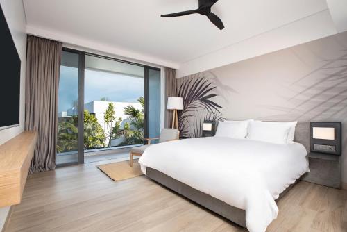 1 dormitorio con cama blanca y ventana grande en Stay Wellbeing & Lifestyle Resort, en Rawai Beach
