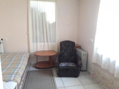 a room with a chair and a table and a bed at Apartment Vishnevyj Pereulok 15 in Odesa