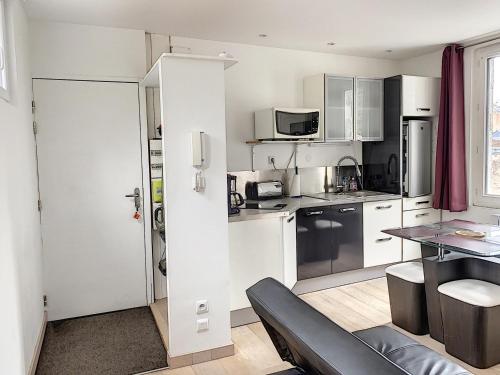 une cuisine avec des placards blancs et une table avec un canapé dans l'établissement Appartement Central avec Terrasse Privative, Ascenseur, et Proche Plage - FR-1-361-353, à Granville