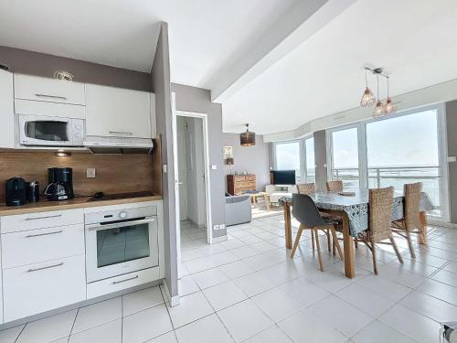 une cuisine et une salle à manger avec une table et des chaises dans l'établissement Bel appartement en front de mer avec balcon, parking et équipements modernes - FR-1-361-327, à Granville