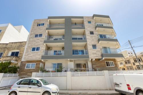a building with two cars parked in front of it at Lavish 3bed In Fair Water Homes Swieqi By Homely in Is-Swieqi