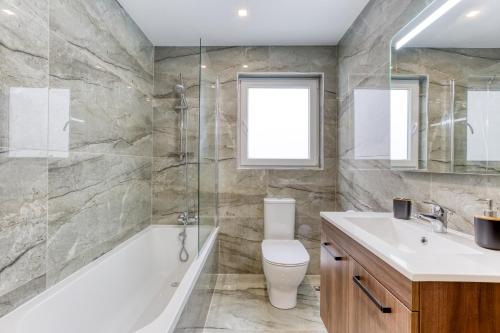a bathroom with a tub and a toilet and a sink at Lavish 3bed In Fair Water Homes Swieqi By Homely in Is-Swieqi
