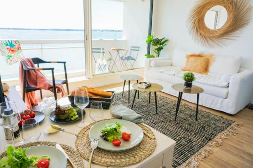 un salon avec une table et des assiettes de nourriture dans l'établissement -Le Phare- Front de mer a Concarneau avec balcon, à Concarneau