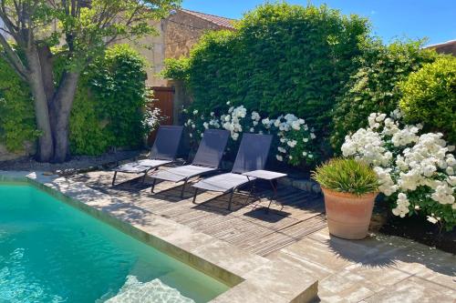 3 chaises assises sur une terrasse à côté d'une piscine dans l'établissement La Maison de Clervie, à Mouriès
