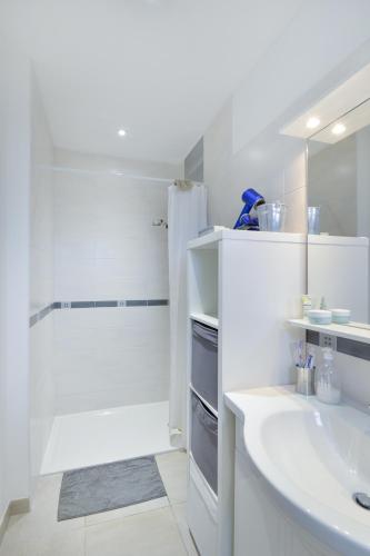 une salle de bain blanche avec un lavabo et une douche dans l'établissement Le Gîte des Tadornes - Pavillon à 5mn de la plage, à Graye-sur-Mer