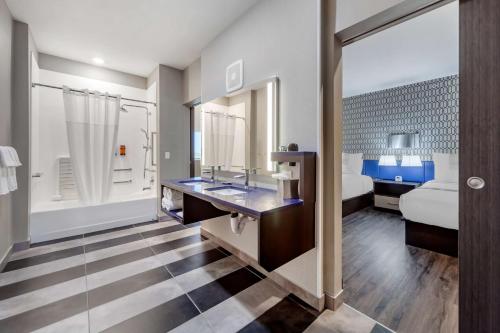 a bathroom with a bed and a sink in a room at GLō Best Western Dawley Farms In Sioux Falls in Sioux Falls