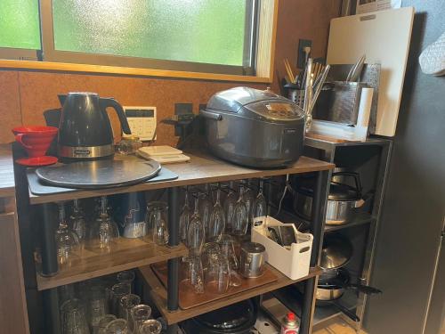 a kitchen with a shelf filled with pots and pans at 大自然に囲まれた築120年の隠れ家古民家で里山リラクゼーション in Isumi