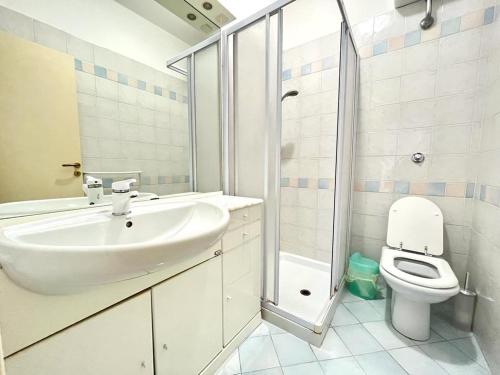 a white bathroom with a sink and a toilet at Pineta Apartament in Tirrenia