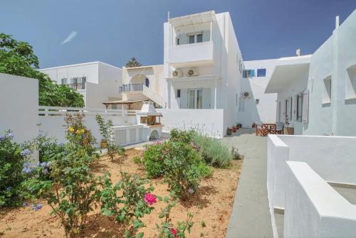 a white house with a garden in front of it at Rose House and Apartments in Andiparos