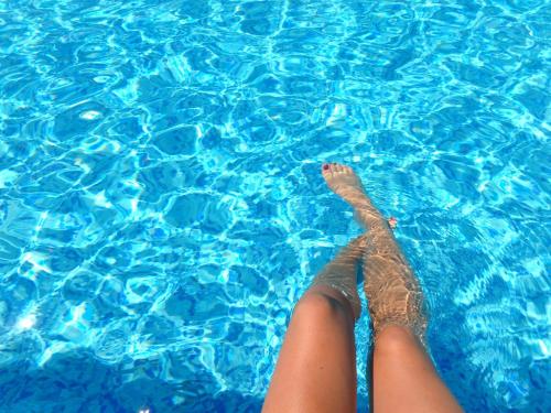 a persons legs in a pool of blue water at Naxian Air in Agios Georgios