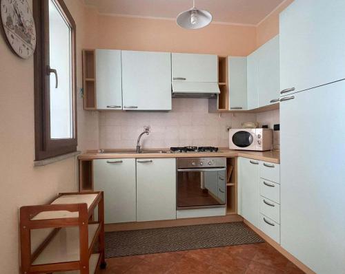a small kitchen with white cabinets and a microwave at Le Residenze Blu Sardinia in La Caletta