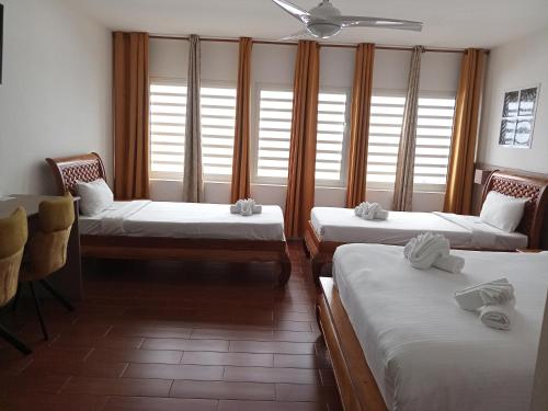 a room with three beds and a table and windows at Hôtel Les Embruns Du Baril in Basse Vallée