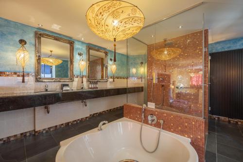 a large bathroom with a tub and a large mirror at Grand Hotel Amrâth Amsterdam in Amsterdam