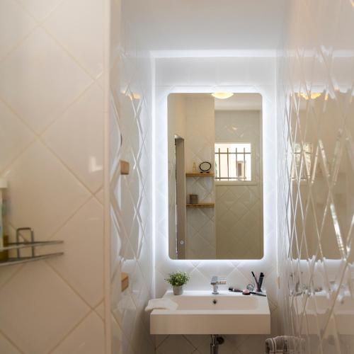 une salle de bain blanche avec un lavabo et un miroir dans l'établissement La maison de Brigitte, à LʼIsle-sur-la-Sorgue