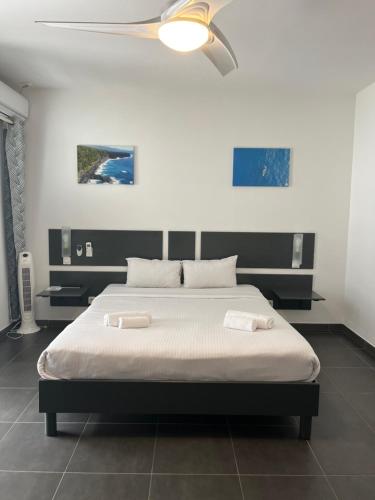 a bedroom with a bed with two white towels on it at Hôtel Les Embruns Du Baril in Basse Vallée