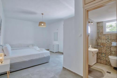a white bedroom with a bed and a bathroom at Rose House and Apartments in Andiparos